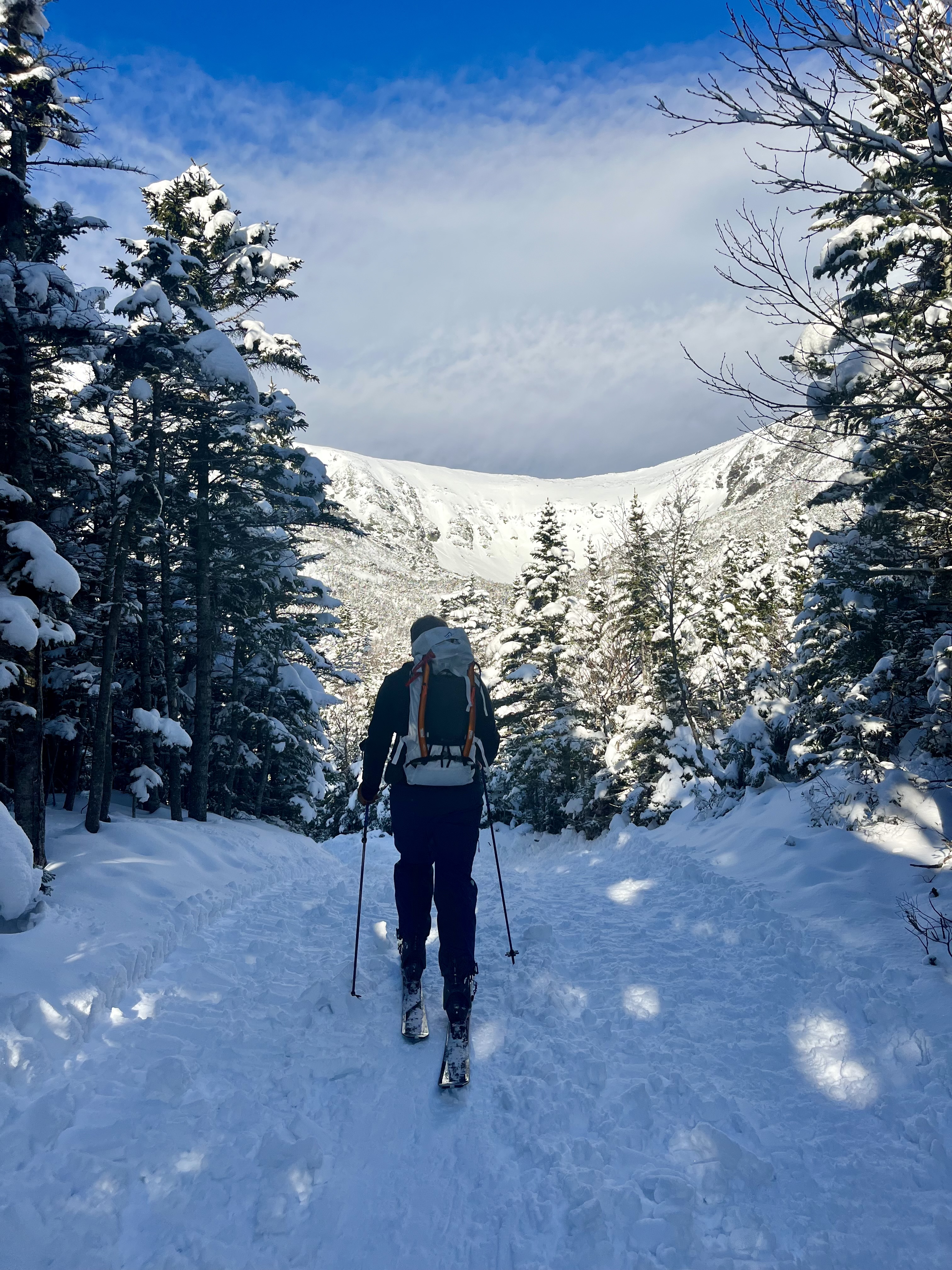 Backcountry ski touring toward a snow-filled mountain bowl
